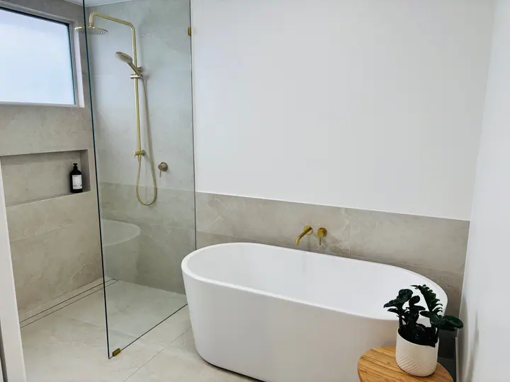 Freestanding bath and walk-in shower with large-format grey wall tiles and a tiled niche