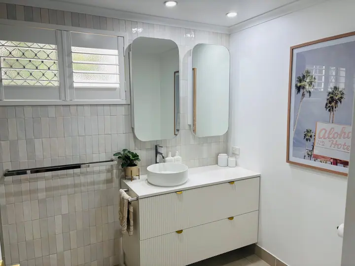 Vanity and towel rail against vertically laid white gloss wall tiles