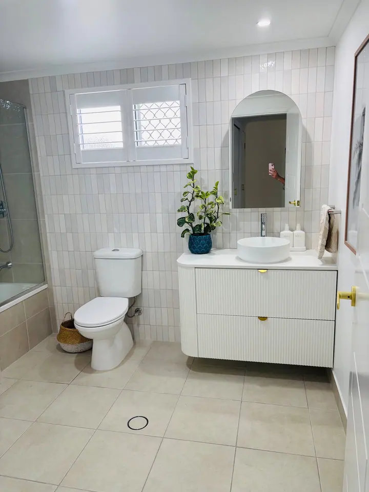 Bathroom with vertically laid white gloss wall tiles, an arched mirror and cream floor tiles