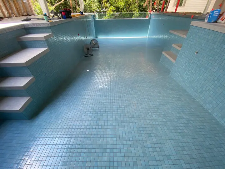 Pool steps and walls tiled in aqua mosaic, ready to fill