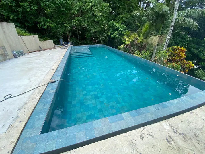 Pool tiled in green-blue tiles surrounded by rainforest