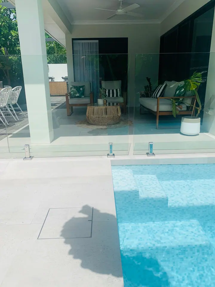 Pool with light blue interior tiles and a pale tiled surround beside a covered patio