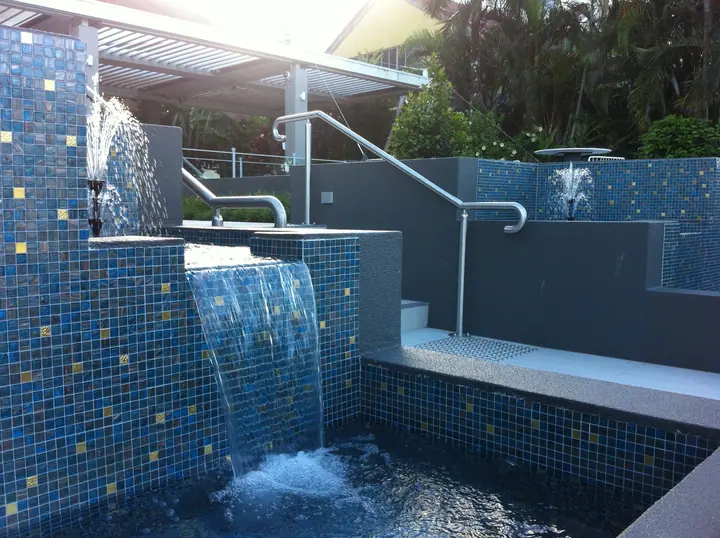 Pool water feature finished in blue and gold glass mosaic tiles